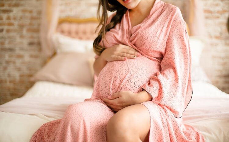 kobieta w ciąży siedzi na łóżku w sypialni